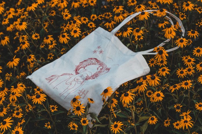 white and brown handbag on bed of sunflowers