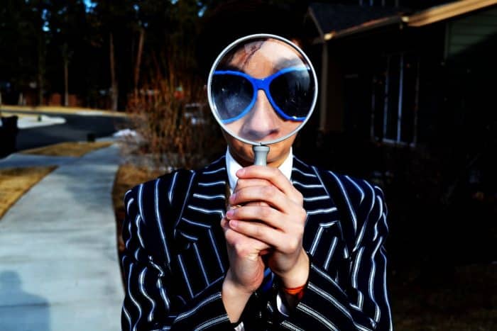 person using magnifying glass enlarging the appearance of his nose and sunglasses